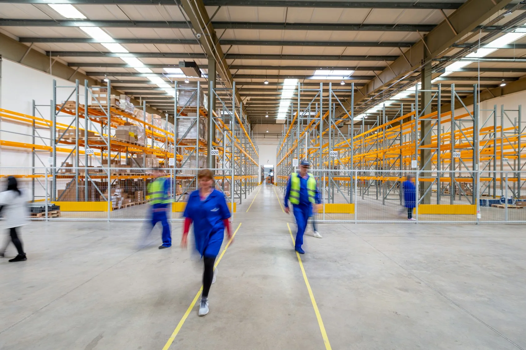 Workers moving through a distribution warehouse aisle while Pulse handles the follow-ups